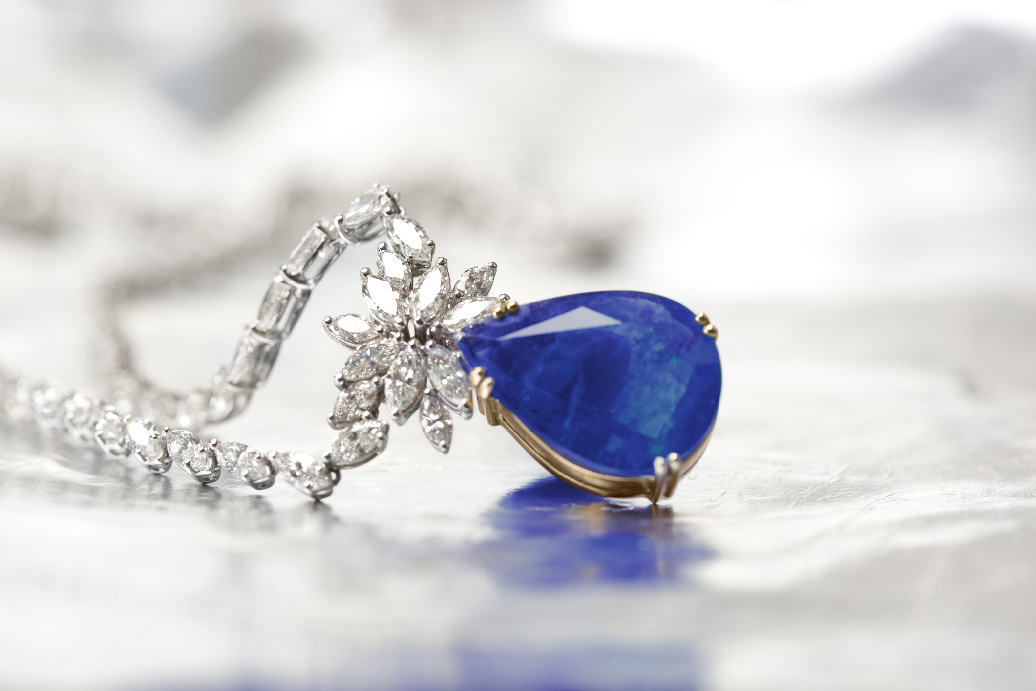 Pendentif en or serti d'une pierre bleue taille poire et de diamants, retouche photo bijouterie sur fond blanc