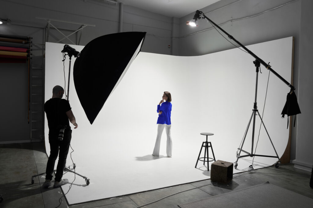 Photographe et mannequin sur un plateau studio en cyclorama blanc, l’un des métiers de l’image que l’IA ne standardise pas.
