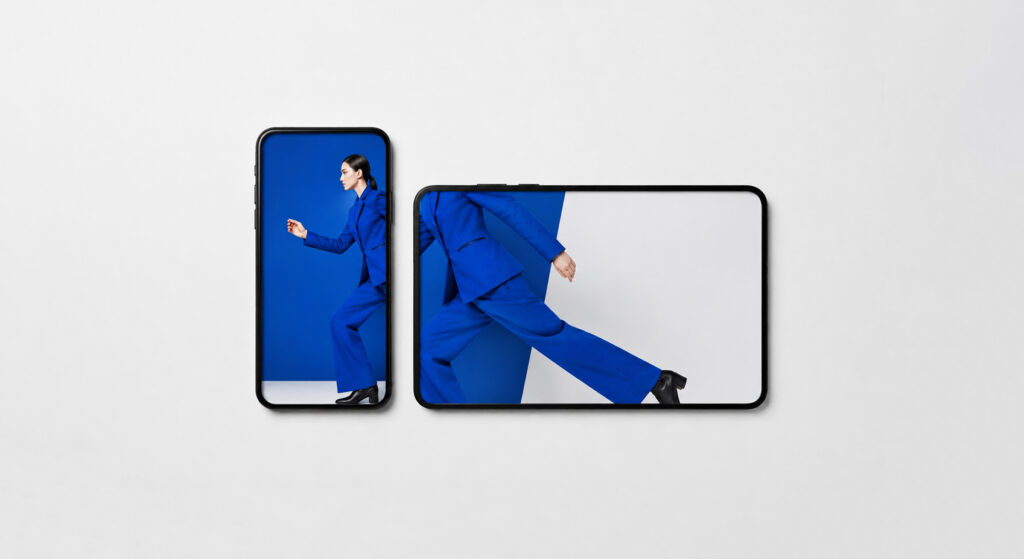 Visuels d’une nouvelle collection de mode : une femme en tailleur bleu en marche, la même photo déclinée en format vertical sur un smartphone et en format large sur une tablette (visuel généré par IA).